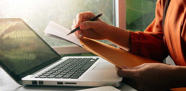 Person writing near laptop